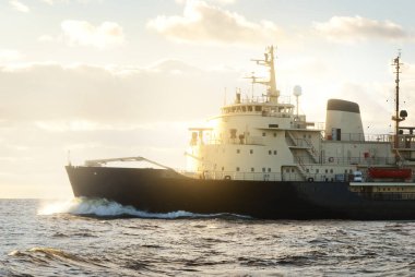 Sovyet buzkıranı dramatik günbatımı bulutları altında açık denizde. Yük taşımacılığı, küresel iletişim ve güvenlik, yakıt ve güç üretimi, sanayi, lojistik, araştırma, keşif