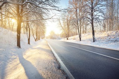 Karla kaplı ormanın içindeki boş otoyolun panoramik görüntüsü. Kırsal kesimde kış manzarası. Seyahat, Noel tatili, lojistik, tehlikeli sürüş, off-road, ulaşım, kış lastikleri, hız, özgürlük