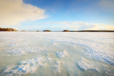 Gün batımında donmuş göl ve karla kaplı çam ormanı. Buz dokusu. Dramatik gökyüzü, yumuşak güneş ışığı. Idyllic kış sahnesi. Doğa, çevre koruma, ekoloji, iklim değişikliği, eko-turizm, Noel