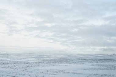 Gün batımında kar fırtınasından sonra karla kaplı arazinin panoramik görüntüsü. Taze karda insan izleri. Buz çölü. Dramatik bulut manzarası. Küresel ısınma teması. Laponya, Finlandiya