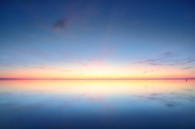 Gün batımında donmuş Saima gölünün karla kaplı kıyılarının panoramik görüntüsü. Göz kamaştırıcı pembe bulutlar. Suyun simetri yansımaları. Kış Harikalar Diyarı. Finlandiya