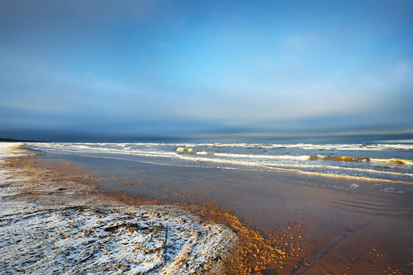 日没時には雪に覆われたバルト海の海岸からの眺め ラトビアのリガ湾 劇的な青空 ひどい天気 波と水が飛び散った 冬の観光 地球温暖化のテーマ — ストック写真