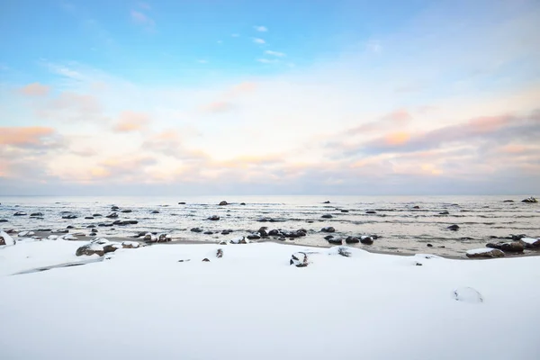 日没の雪に覆われたバルト海沿岸の景色 水の中の石を閉じる カラフルな雲と澄んだ青い空 見事な雲景だ 暖かい夜の光 牧歌的な冬のシーン ラトビアのカルテネ — ストック写真
