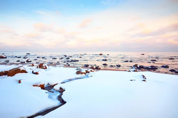 日没の雪に覆われたバルト海沿岸の景色 水の中の石を閉じる カラフルな雲と澄んだ青い空 見事な雲景だ 暖かい夜の光 牧歌的な冬のシーン ラトビアのカルテネ — ストック写真