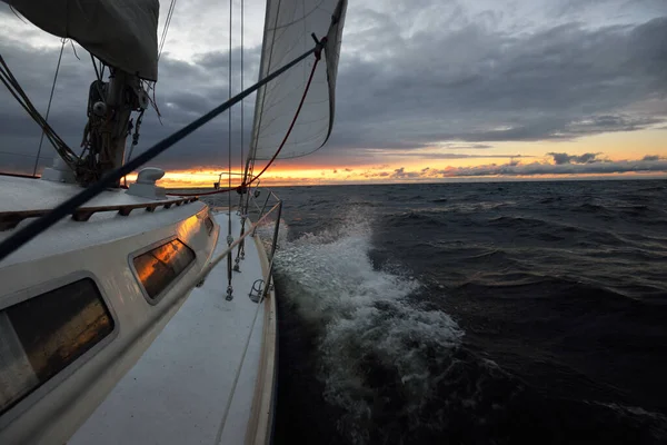 日没の冬の日に屋外の海でヨットセーリング デッキから弓 マスト 帆へのクローズアップビュー 劇的な空 暗い雲を介して黄金の太陽の光 壮大な海の景色 ノルウェー — ストック写真