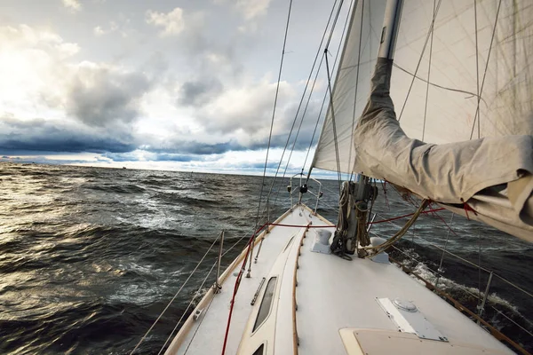 Bir kış günü açık denizde yat gezintisi. Güverteden pruvaya, direğe ve yelkenlere yakın görüntü. Fırtınadan sonra dramatik bir gökyüzü, parlak bulutlar. Destansı deniz manzarası. Kuzey denizi, Norveç