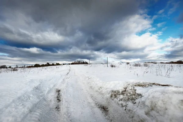 吹雪の後に雪に覆われたフィールドを空の道路 輝く雲と劇的な空 冬の田園風景 旅行先 エコツーリズム オフロード 遠隔村 — ストック写真