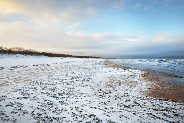 夕暮れ時には雪に覆われたバルト海の海岸からの眺め ラトビアのリガ湾 カラフルな劇的な雲の風景 ひどい天気 波と水が飛び散った 冬の観光 地球温暖化のテーマ — ストック写真