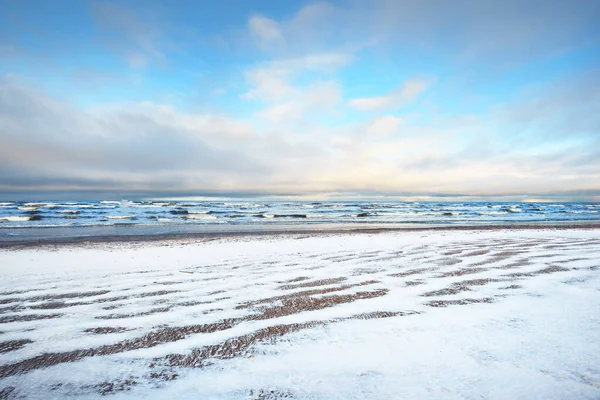 夕暮れ時には雪に覆われたバルト海の海岸からの眺め ラトビアのリガ湾 カラフルな劇的な雲の風景 ひどい天気 波と水が飛び散った 冬の観光 地球温暖化のテーマ — ストック写真