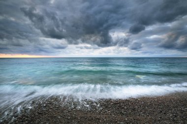 Gün batımında Etretat kayalıklarının yakınındaki kayalık sahil manzarası. Renkli akşam bulutları. Normandiya, Fransa. Dramatik deniz manzarası. Seyahat yerleri, ulusal dönüm noktası, çevresel koruma