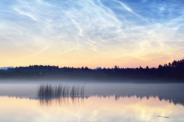 Yaz gündönümü gecesinde Saimaa Gölü 'nün üzerinde gece parlayan bulutlar ve sis vardı. Altın güneş ışığı. Uzun pozlama. Destansı bulut manzarası. Doğal desen. Suyun simetri yansımaları. Finlandiya