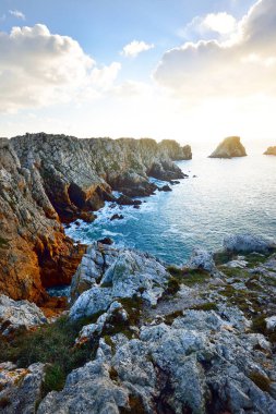 Pointe de Pen-Hir 'in kayalık sahili, uçurumlara yakın. Bulutlu mavi gökyüzü, masmavi su, fırtınalı dalgalar. Dramatik bulut manzarası. Crozon Yarımadası, Britanya, Fransa