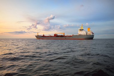 Büyük gri bir tanker gün batımında Europort 'tan denize açılacak. Renkli akşam bulutları. Rotterdam, Hollanda. Lojistik, ticaret, küresel iletişim teması