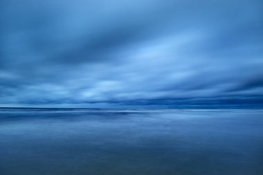 Kışın Kuzey Denizi 'nin yukarısında fırtına bulutları, uzun pozlama. Dramatik gökyüzü, dalgalar ve su sıçramaları. Koyu deniz manzarası. Hollanda