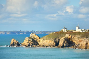 Pointe de Pen-Hir 'in kayalık sahili, uçurumlara yakın. Bulutlu mavi gökyüzü, masmavi su, fırtınalı dalgalar. Dramatik bulut manzarası. Crozon Yarımadası, Britanya, Fransa