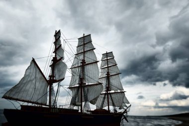 Kırpıcı uzunluğundaki geminin antik ahşap ölçekli modeli, yakın plan. Arka planda dramatik bir gökyüzü. Geleneksel zanaat, hediyelik eşya, hobi, koleksiyon, antika, modellik. Sıfır atık