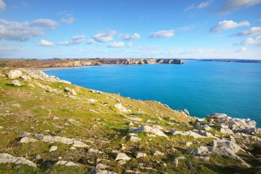 Pointe de Pen-Hir 'in kayalık sahili, uçurumlara yakın. Bulutlu mavi gökyüzü, masmavi su, fırtınalı dalgalar. Dramatik bulut manzarası. Crozon Yarımadası, Britanya, Fransa