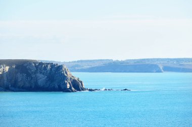 Pointe de Pen-Hir 'in kayalık sahili, uçurumlara yakın. Bulutlu mavi gökyüzü, masmavi su, fırtınalı dalgalar. Dramatik bulut manzarası. Crozon Yarımadası, Britanya, Fransa