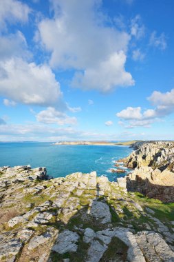 Pointe de Pen-Hir 'in kayalık sahili, uçurumlara yakın. Bulutlu mavi gökyüzü, masmavi su, fırtınalı dalgalar. Dramatik bulut manzarası. Crozon Yarımadası, Britanya, Fransa