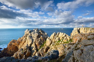 Pointe de Pen-Hir 'in kayalık sahili, uçurumlara yakın. Bulutlu mavi gökyüzü, masmavi su, fırtınalı dalgalar. Dramatik bulut manzarası. Crozon Yarımadası, Britanya, Fransa
