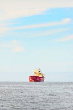 Europoort 'tan denize açılan bir vinçle büyük kırmızı bir yük gemisi (kargo gemisi). Açık mavi gökyüzü ve sirrus bulutları. Rotterdam, Hollanda. Küresel iletişim, lojistik, endüstri teması