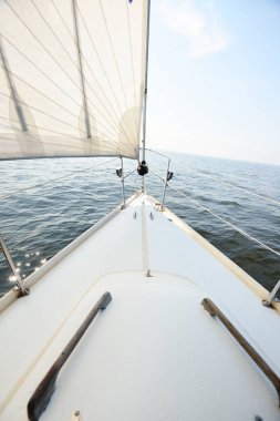 Güneşli bir yaz gününde beyaz bir yat denize açılıyor. Güverteden pruvaya, direğe ve yelkenlere kadar yukarıdan aşağı görüş. Dalgalar ve su sıçramaları. Açık mavi gökyüzü. Finlandiya Körfezi