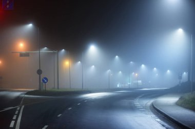 Gece sisli bir ortamda bomboş bir otoyol. Sokak lambaları ve yol işaretleri yakın. Karanlık şehir manzarası, şehir manzarası. Riga, Letonya. Tehlikeli sürüş, hız, özgürlük, konsept görüntü
