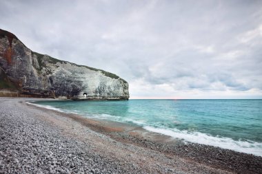 Gün batımında uçurum ve kayalık deniz kıyısında. Etretat, İngiliz kanalı, Normandiya, Fransa. Destansı renkli bulut manzarası. Ulusal dönüm noktası, seyahat yerleri, gezi teması. Uzun pozlama