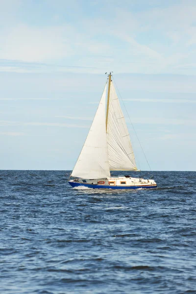 Small yacht sailing near the lighthouse on a clear day. Riga bay, Baltic sea, Latvia. Cruise, sport, recreation, leisure activity concepts