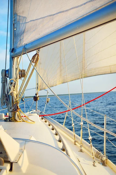 White sailboat in an open sea on a clear sunny day, close-up view from the deck to the bow, mast and sails. Single handed sailing a 34 ft yacht. England, UK. Sport, racing, recreation