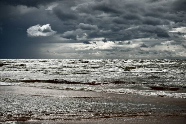 Baltic sea under the dark dramatic clouds after thunderstorm. Latvia. Epic seascape. Cyclone, gale, storm, rough weather, meteorology, ecology, climate change, natural phenomenon