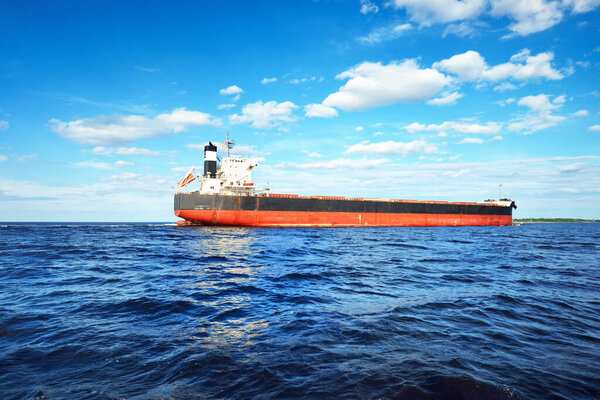 Large bulk carrier (ship) sailing in the Baltic sea to Riga port, Latvia. A view from the yacht. General cargo. Global communications, logistics, industry, freight transportation