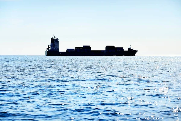 Large cargo container ship sailing from Europoort (Rotterdam, Netherlands) on a clear day, close-up. Freight transportation, global communications, logistics, environmental damage theme