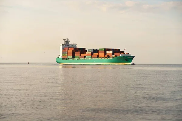 Large cargo container ship sailing from Europoort (Rotterdam, Netherlands) in an open sea on a clear day, close-up. Freight transportation, global communications, logistics, environmental damage theme