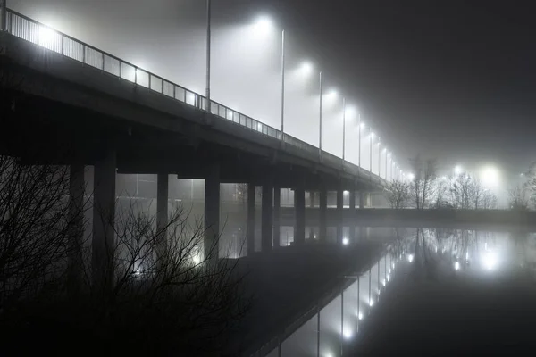 夜雾中灯火通明的空桥的低角度视图 灯笼特写 对称反射在水面上 天然的镜子 Daugava河 拉脱维亚里加 — 图库照片