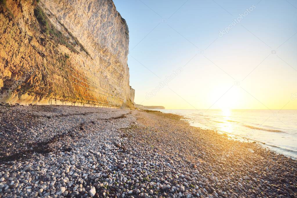 White cliff on the rocky shore of English Channel at sunset. Fcamp, Normandy, France. Clear blue sky. Nature, history, past, national landmark, sightseeing, travel destinations.