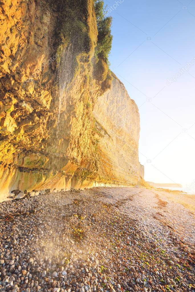 White cliff on the rocky shore of English Channel at sunset. Fcamp, Normandy, France. Clear blue sky. Nature, history, past, national landmark, sightseeing, travel destinations.