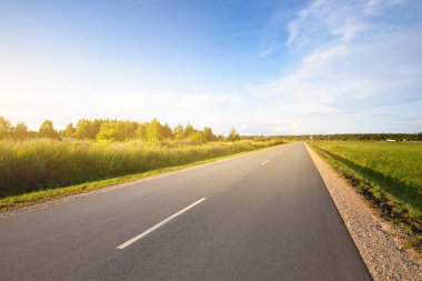 Letonya 'nın yeşil ülke tarım sahasından geçen boş bir otoyol (yeni asfalt). Yağmurdan sonra dramatik bulutlar. Idyllic yaz kırsal manzarası. Tehlikeli sürüş, özgürlük konsepti