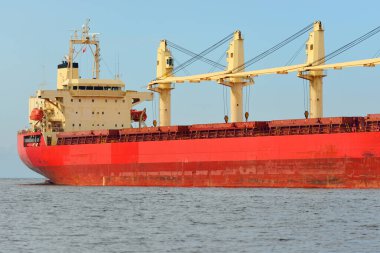 Europoort 'tan denize açılan bir vinçle büyük kırmızı bir yük gemisi (kargo gemisi). Açık mavi gökyüzü ve sirrus bulutları. Rotterdam, Hollanda. Küresel iletişim, lojistik, endüstri teması