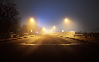 Boş, aydınlık bir otoyol ve gece sisli bir havada kapalı dükkanlar. Yol tabelası yakın plan. Karanlık şehir manzarası, şehir manzarası. Riga, Letonya. Tehlikeli sürüş, konsept görüntü