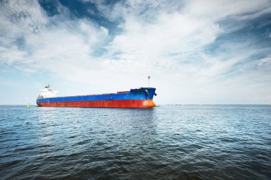 Büyük mavi yük gemisi (kargo gemisi) Baltık Denizi 'nden Letonya' nın Riga limanına gidiyor. Yattan bir manzara. Dramatik bulut manzarası. Küresel iletişim, lojistik, endüstri teması