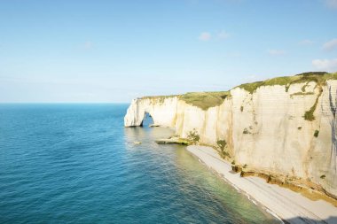 Gün batımında Etretat beyaz uçurumlarının manzaralı panoramik görüntüsü. Dramatik gökyüzü, gök mavisi su. Fransa, Normandiya 'da yaz tatili. Seyahat yerleri, ulusal dönüm noktaları, geziler, tarih.