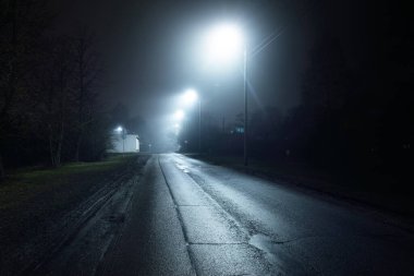 Geceleyin sislerin içinde boş eski bir asfalt yol. Sokak Işıkları yakın plan. Karanlık şehir manzarası, şehir manzarası. Riga, Letonya. Tehlikeli sürüş, hız, özgürlük, konsept görüntü
