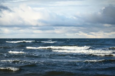 Baltık Denizi üzerinde fırtına bulutları, kışın kasırga. Gün batımının destansı gökyüzü, dalgalar ve su sıçramaları. Koyu deniz manzarası. Almanya. Ekoloji, iklim değişikliği, küresel ısınma kavramları