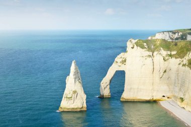 Gün batımında Etretat beyaz uçurumlarının manzaralı panoramik görüntüsü. Dramatik gökyüzü, gök mavisi su. Fransa, Normandiya 'da yaz tatili. Seyahat yerleri, ulusal dönüm noktaları, geziler, tarih.