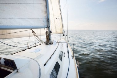 Açık denizde, açık bir günde beyaz bir yat. Güverteden pruvaya kadar tepeden aşağı görüş, direk ve yelkenler, ekipmanları yakın çekim. Yaz Atlantik 'i İspanya ve Afrika yakınlarında geçiyor.