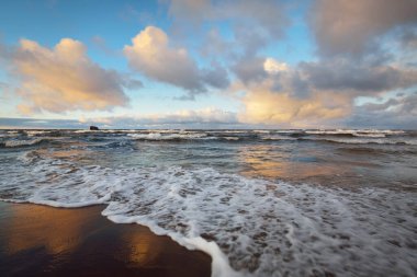 Baltık Denizi 'nin üzerindeki renkli günbatımı bulutları, kışın kasırga. Dramatik gökyüzü, dalgalar ve su sıçramaları. Almanya. Ekoloji, iklim değişikliği, küresel ısınma kavramları