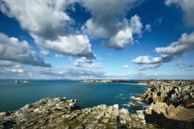 Pointe de Pen-Hir 'in kayalık sahili, uçurumlara yakın. Bulutlu mavi gökyüzü, masmavi su, fırtınalı dalgalar. Dramatik bulut manzarası. Crozon Yarımadası, Britanya, Fransa