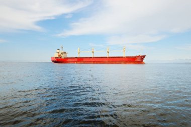 Europoort 'tan denize açılan bir vinçle büyük kırmızı bir yük gemisi (kargo gemisi). Açık mavi gökyüzü ve sirrus bulutları. Rotterdam, Hollanda. Küresel iletişim, lojistik, endüstri teması
