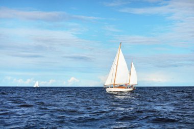 Old expensive vintage wooden sailboat (yawl) close-up, sailing in an open sea. Stunning cloudscape. Coast of Maine, US clipart